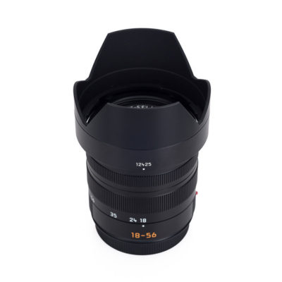 Leica Vario-Elmar T 18-56mm f/3.5-5.6 ASPH T-mount - Tweedehands met een zwarte behuizing en zonnekap, zichtbaar zijn de scherpstelmarkeringen en zoomring.