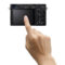 Sony DSC RX1R III toont de achterkant met een touchscreen en bedieningselementen, terwijl een hand het scherm aanraakt.